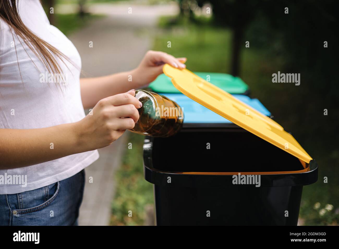 Primo piano ritratto donna lancio a mano vuota bottiglia d'acqua di plastica in contenitore di riciclaggio Foto Stock