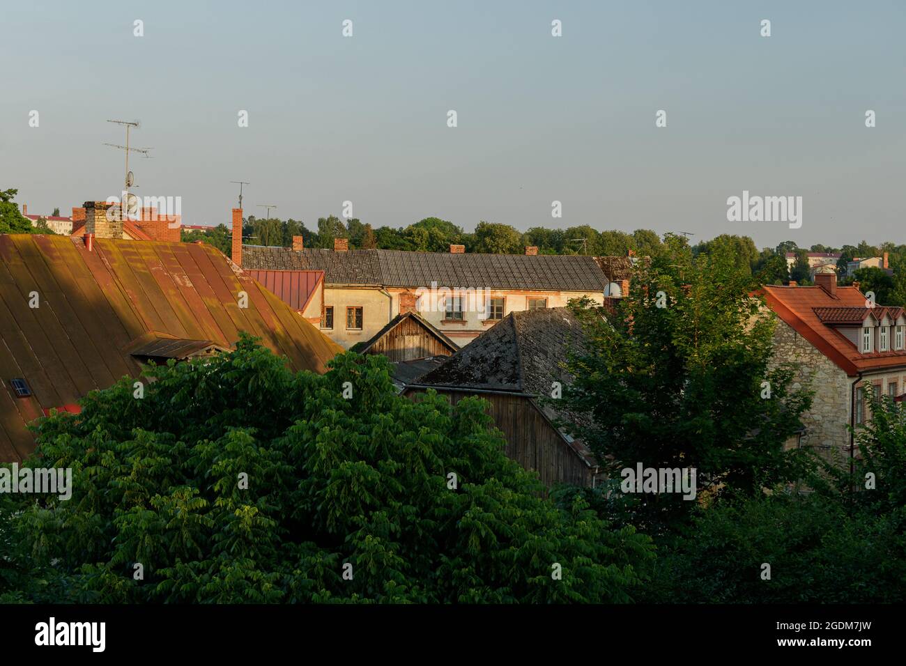 Alba estiva, cinque al mattino. Vista dei tetti di Cēsis dalla finestra del quarto piano. Tetti rossi, vecchi, arrugginiti, vecchie case in legno, lucernario Foto Stock