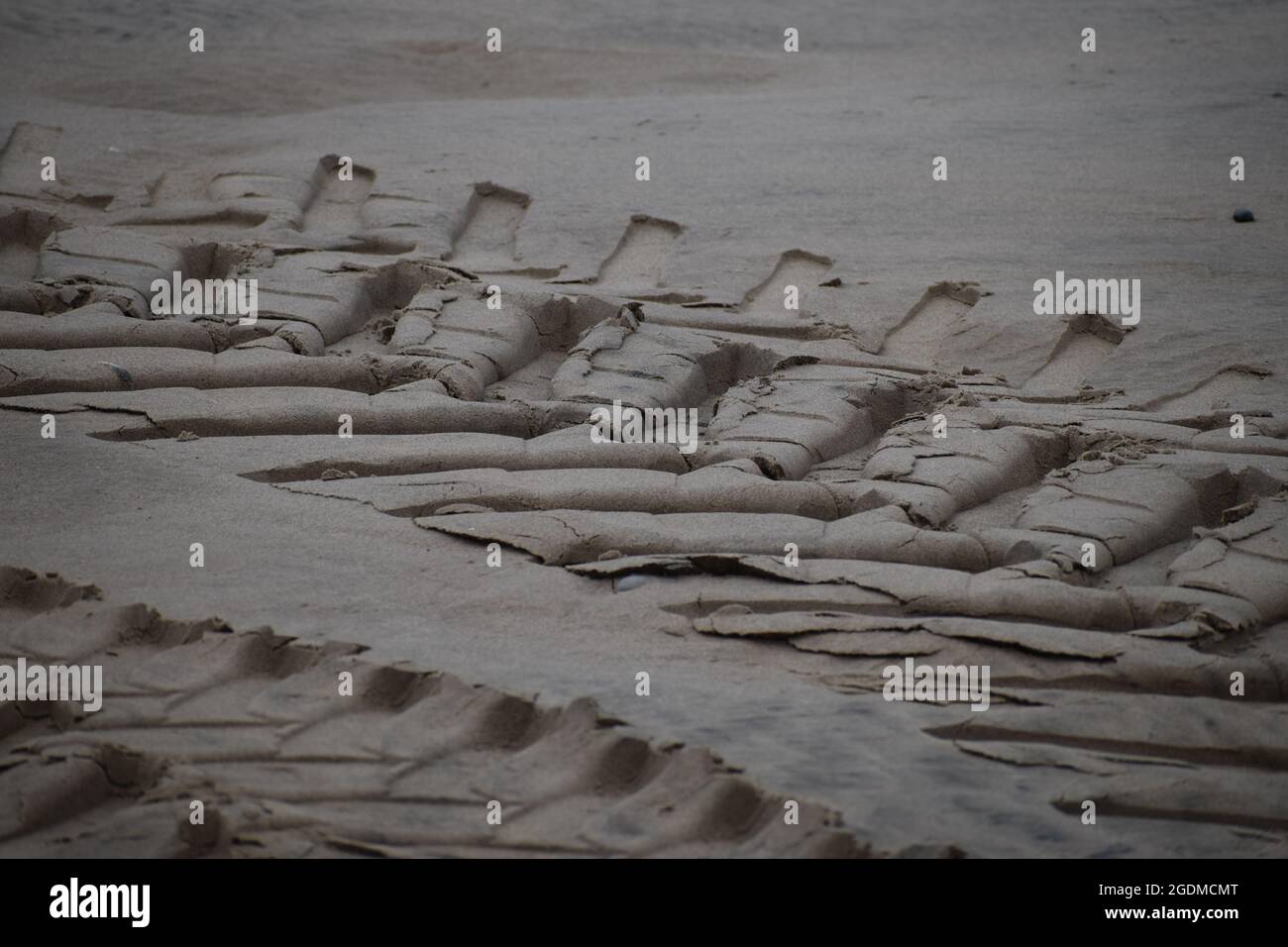 Cingoli pneumatici del trattore su una spiaggia sabbiosa Foto Stock