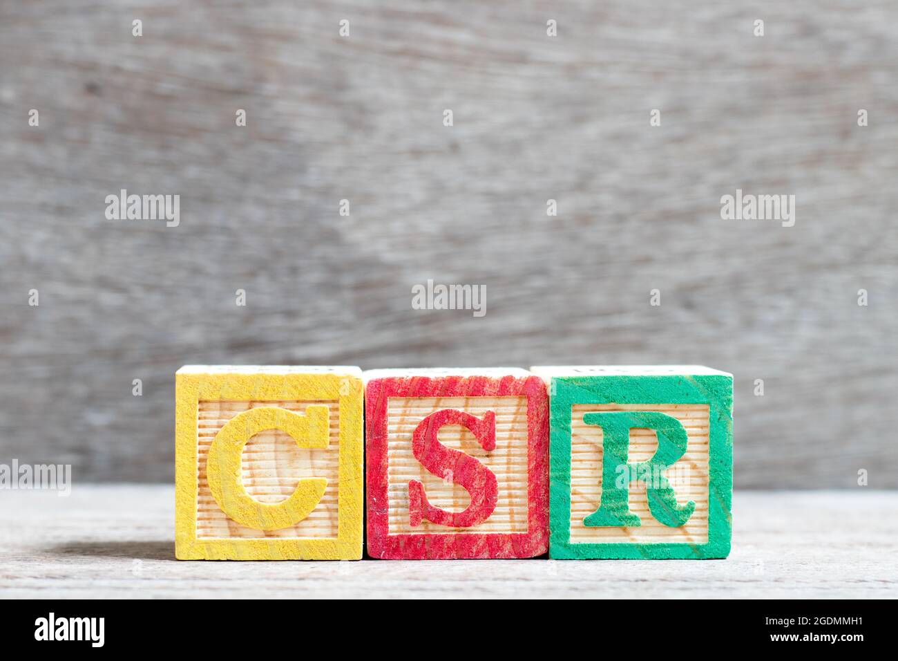 Colore blocco lettera nella parola CSR (abbreviazione di corporate social responsibility) su uno sfondo di legno Foto Stock