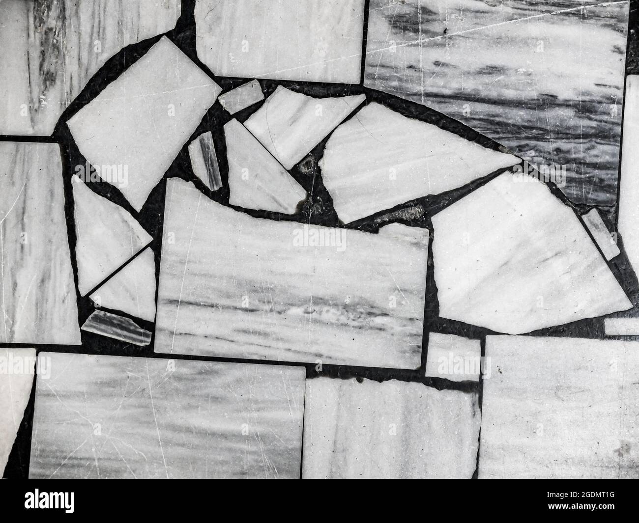 Vista dall'alto del vecchio pavimento, fatto di pezzi di varie dimensioni in marmo bianco e grigio. Sfondo a mosaico bianco e nero astratto. Foto Stock