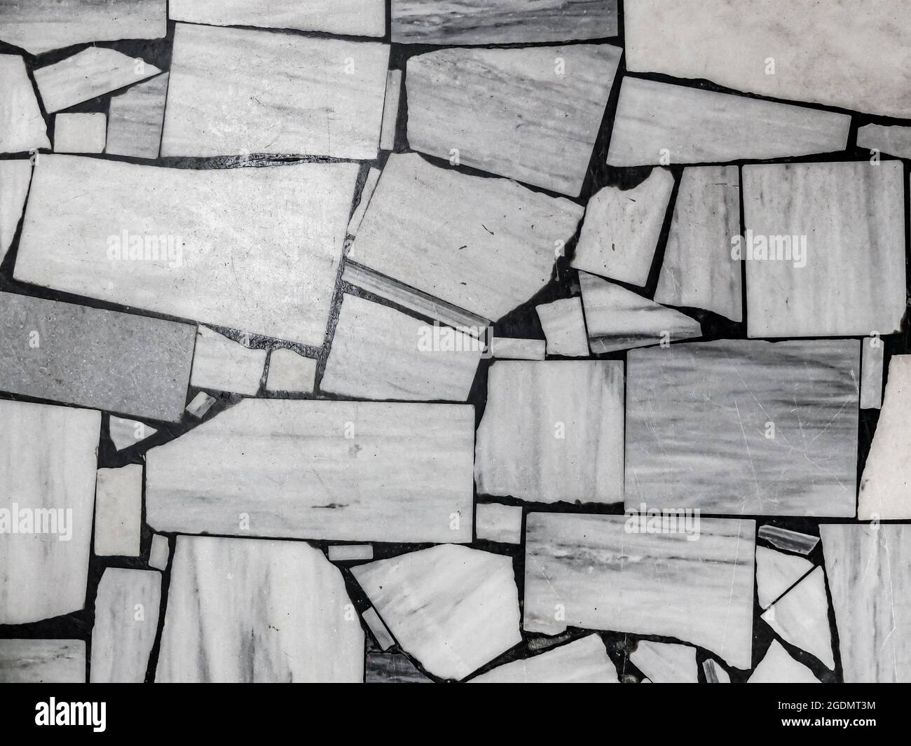 Vista dall'alto del vecchio pavimento, fatto di pezzi di varie dimensioni in marmo bianco e grigio. Sfondo a mosaico bianco e nero astratto. Foto Stock