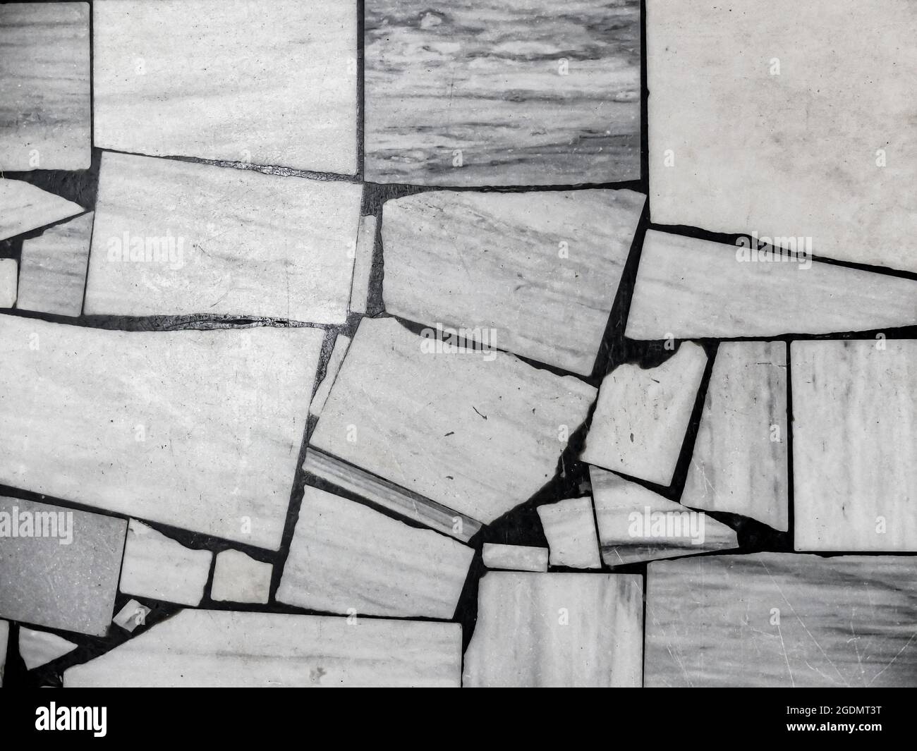 Vista dall'alto del vecchio pavimento, fatto di pezzi di varie dimensioni in marmo bianco e grigio. Sfondo a mosaico bianco e nero astratto. Foto Stock