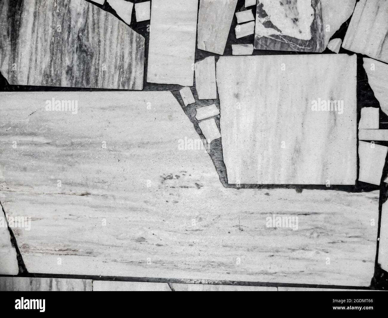 Vista dall'alto del vecchio pavimento, fatto di pezzi di varie dimensioni in marmo bianco e grigio. Sfondo a mosaico bianco e nero astratto. Foto Stock