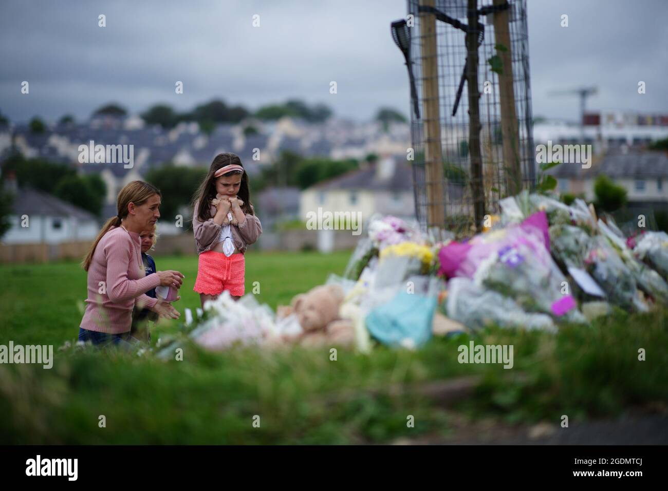Una donna e due giovani ragazze guardano i tributi floreali a Plymouth, dove sei persone, tra cui l'offensore, sono morte di ferite da sparo in un incidente di armi da fuoco il giovedì sera. Data immagine: Sabato 14 agosto 2021. Foto Stock