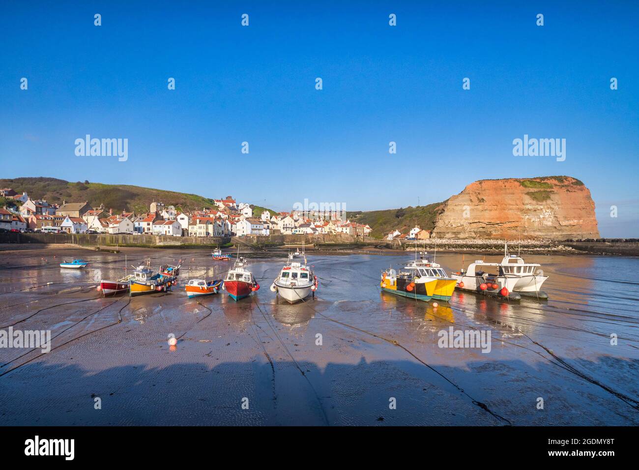 Barche da pesca a terra con bassa marea nel porto di Staithes, North Yorkshire. Foto Stock