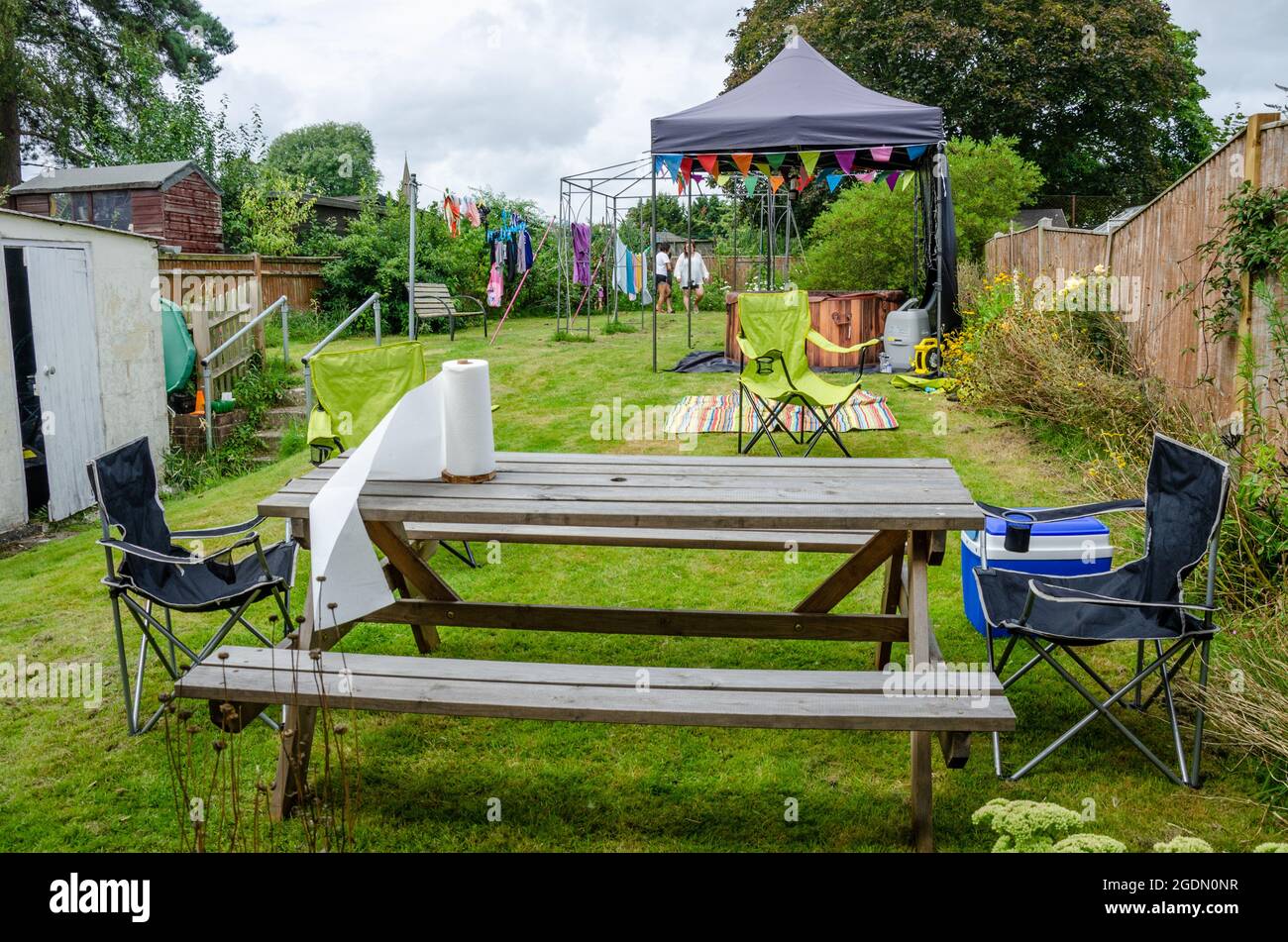 Un giardino allestito per intrattenere con un tavolo di legno e panca posto nella foregrounnd affittato vasca calda sotto un gazebo dietro. Foto Stock