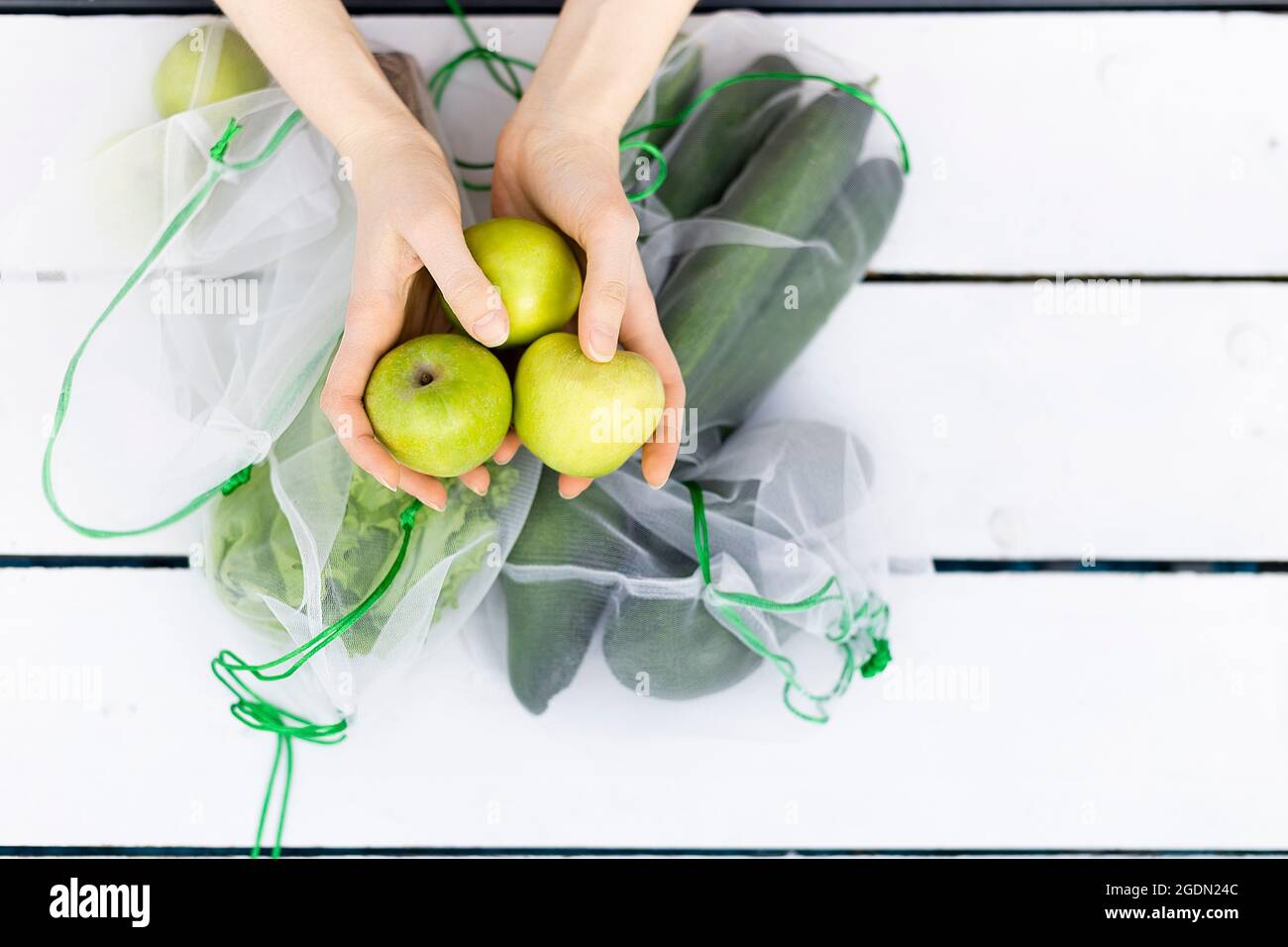 Da sopra di tre mele verdi nelle mani della giovane donna Foto Stock