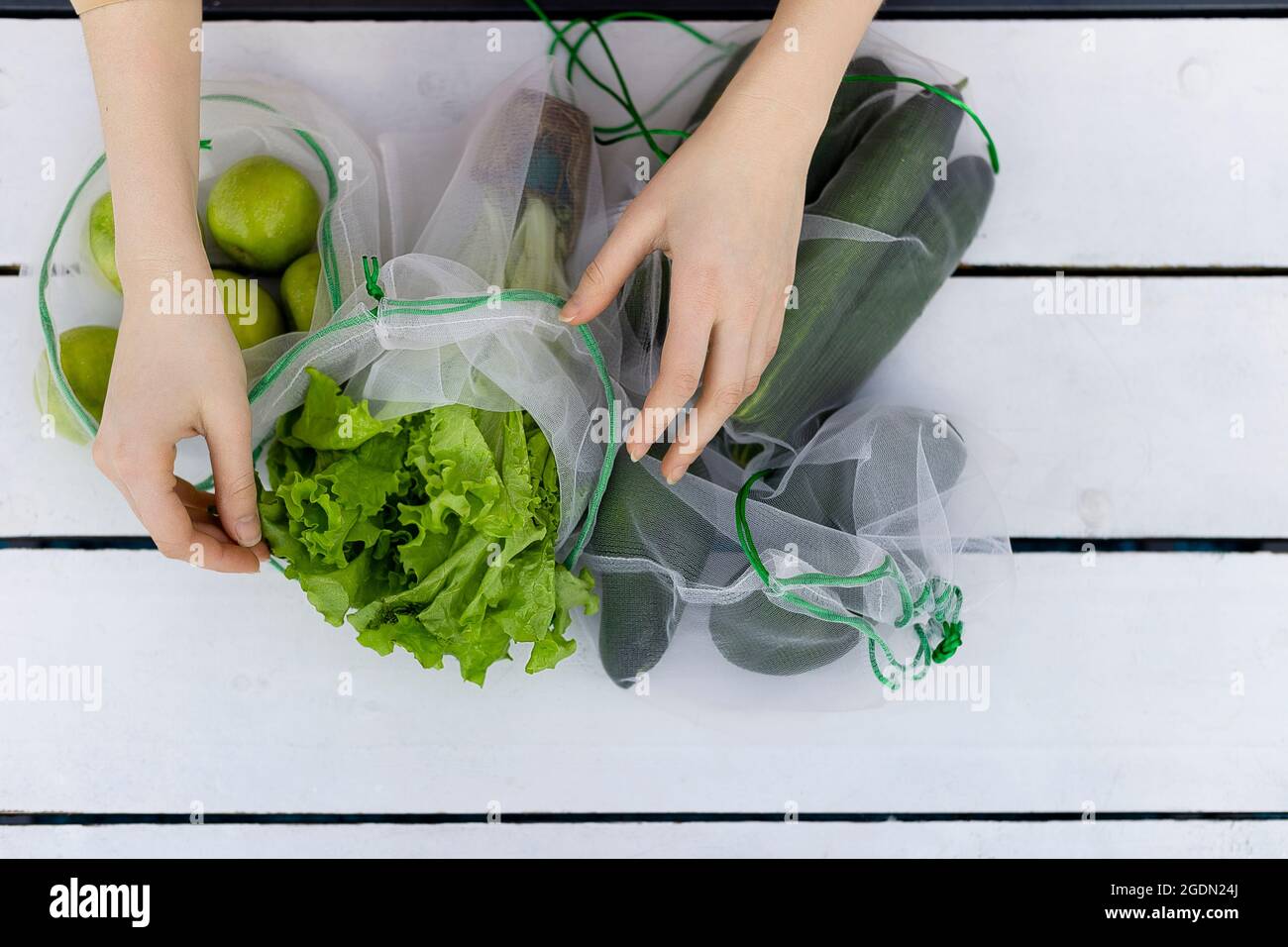 Vista dall'alto della lattuga in sacchetto riutilizzabile nelle mani della giovane donna Foto Stock
