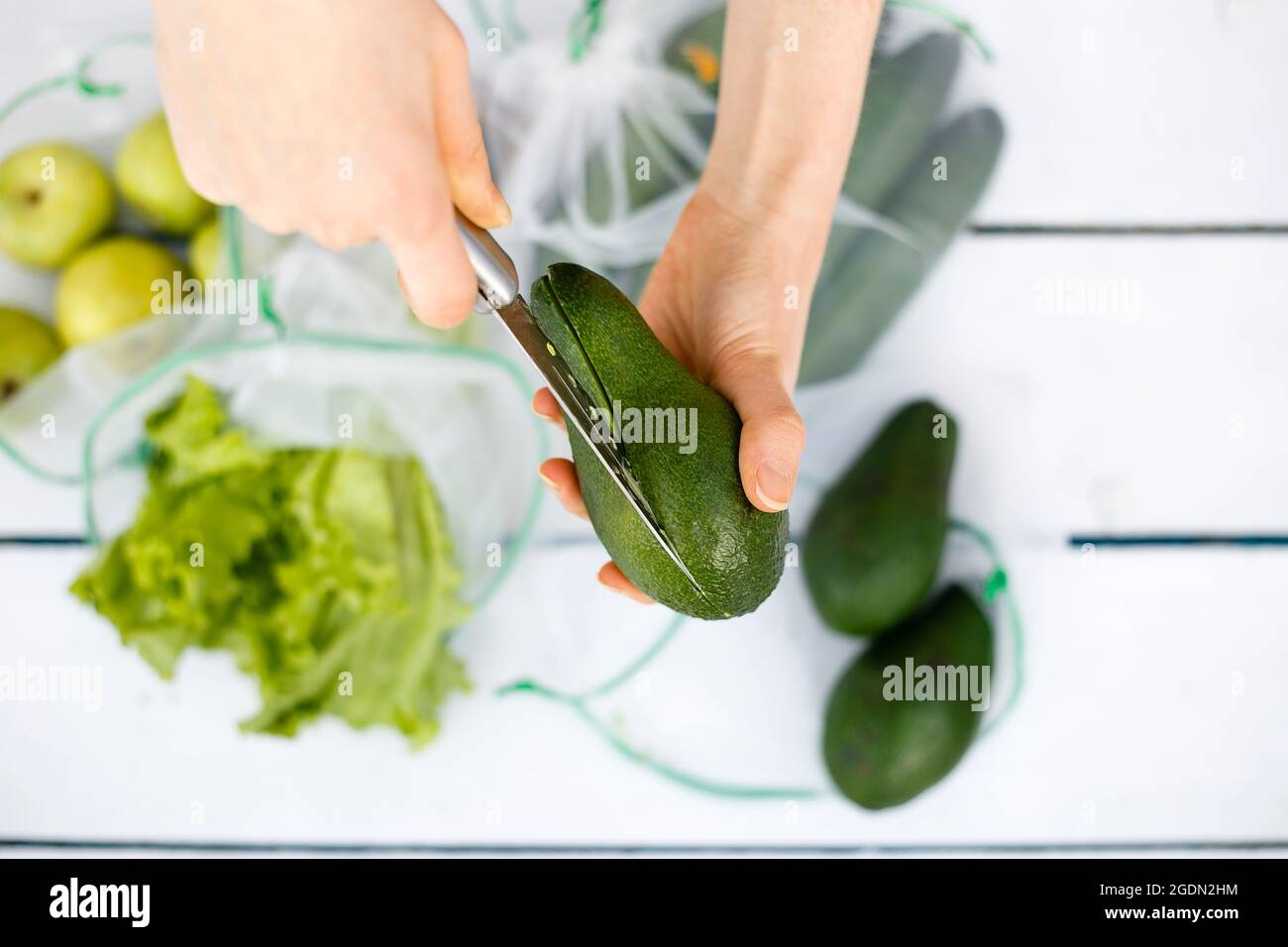Vista dall'alto del coltello taglio l'avocado in mano giovane donna Foto Stock