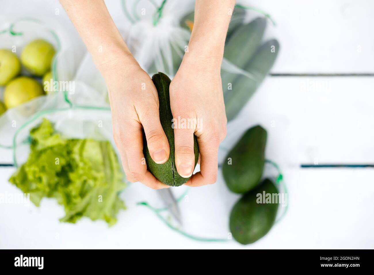 Vista dall'alto del taglio dell'avocado nelle mani delle giovani donne Foto Stock