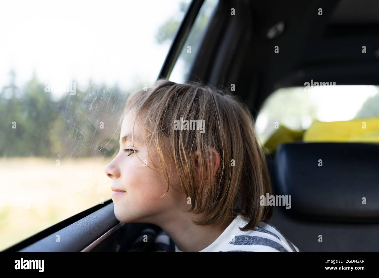 Ragazzo che guarda fuori dalla finestra dell'auto durante un viaggio su strada Foto Stock