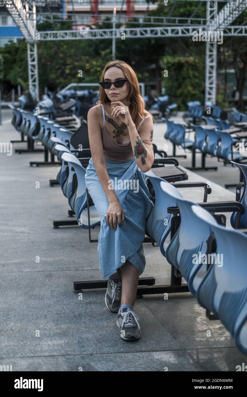 Ritratto a tutta lunghezza di giovane donna elegante sullo stadio. Indossare abiti casual, occhiali da sole e scarpe da ginnastica. Foto di alta qualità Foto Stock