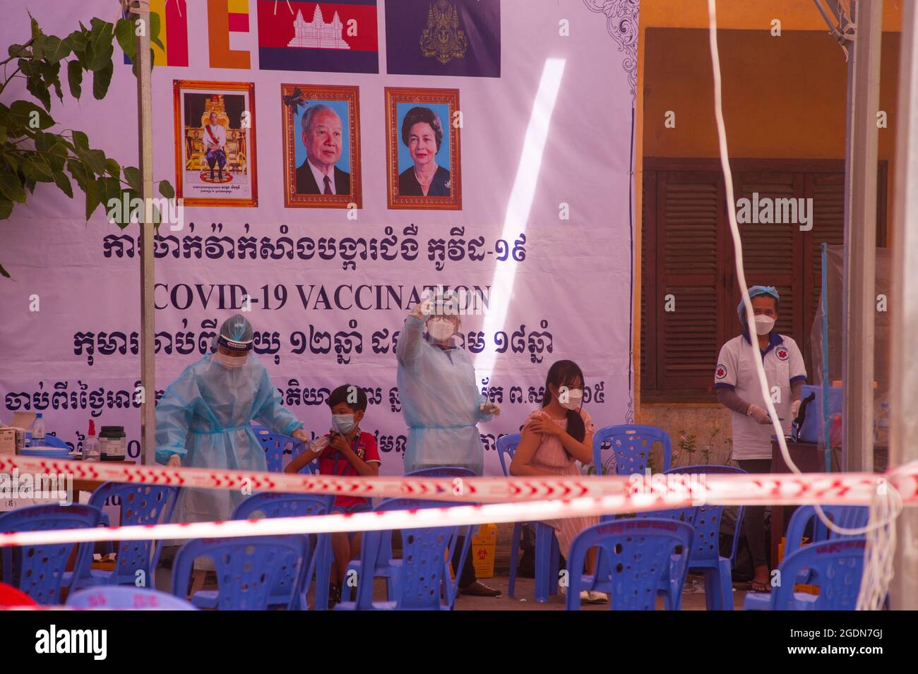 Phnom Penh, Cambogia. 14 agosto 2021. Per oltre 5 mesi Phnom Penh sta combattendo un COVID - 19 aumento. Il governo cambogiano rimane sul corso con il suo programma di vaccinazione per i bambini da 12 a 17 anni in un sito di vaccinazione di massa. EMT / farmaci in PPE pieno somministrare i vaccini agli adolescenti. Un medico controlla il jab. Credito: Kraig Lieb / Alamy Live News Foto Stock