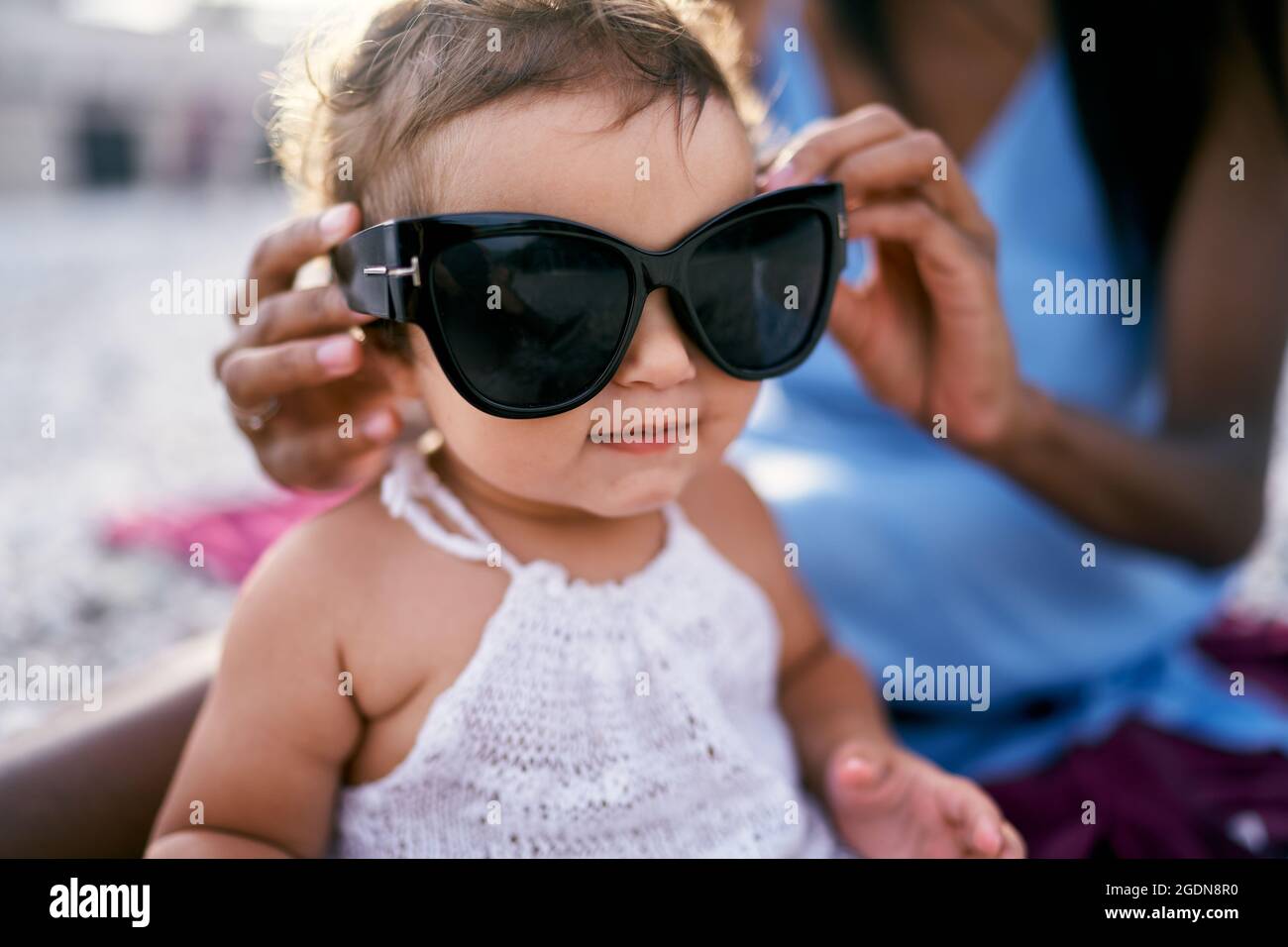 Mamma mette grandi occhiali da sole su una bambina Foto stock - Alamy