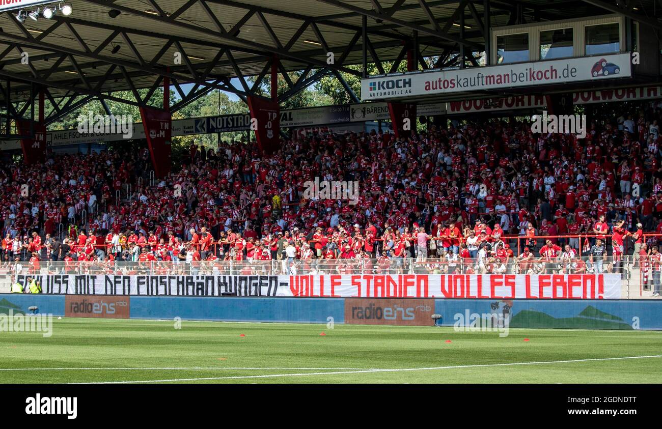 Berlino, Germania. 14 agosto 2021. Calcio: Bundesliga, 1. FC Union Berlin - Bayer Leverkusen, giorno 1, Stadion an der Alten Försterei. I fan si levano in piedi dietro un banner con la scritta "fine delle restrizioni - stadi pieni, vita piena!" Credito: Andreas Gora/dpa - NOTA IMPORTANTE: In conformità con le norme del DFL Deutsche Fußball Liga e/o del DFB Deutscher Fußball-Bund, è vietato utilizzare o utilizzare fotografie scattate nello stadio e/o della partita sotto forma di sequenze fotografiche e/o serie fotografiche di tipo video./dpa/Alamy Live News Foto Stock