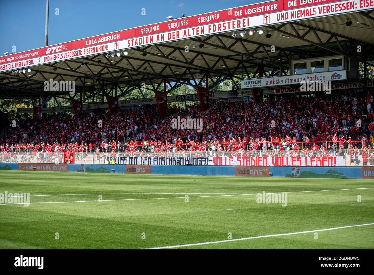 Berlino, Germania. 14 agosto 2021. Calcio: Bundesliga, 1. FC Union Berlin - Bayer Leverkusen, giorno 1, Stadion an der Alten Försterei. I fan si levano in piedi dietro un banner con la scritta "fine delle restrizioni - stadi pieni, vita piena!" Credito: Andreas Gora/dpa - NOTA IMPORTANTE: In conformità con le norme del DFL Deutsche Fußball Liga e/o del DFB Deutscher Fußball-Bund, è vietato utilizzare o utilizzare fotografie scattate nello stadio e/o della partita sotto forma di sequenze fotografiche e/o serie fotografiche di tipo video./dpa/Alamy Live News Foto Stock