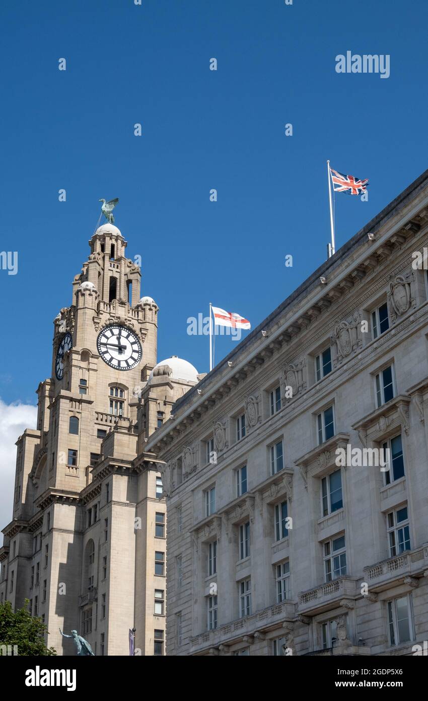 La torre dell'orologio del Royal Liver Building, una delle tre grazie, a Liverpool -- uccelli del fegato e bandiera britannica e bandiera inglese Foto Stock