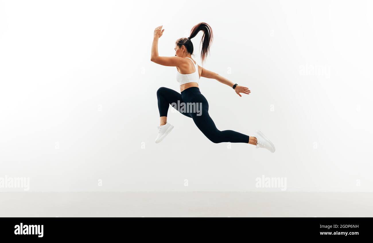 Atleta femminile che corre e salta contro il backgroung bianco Foto Stock