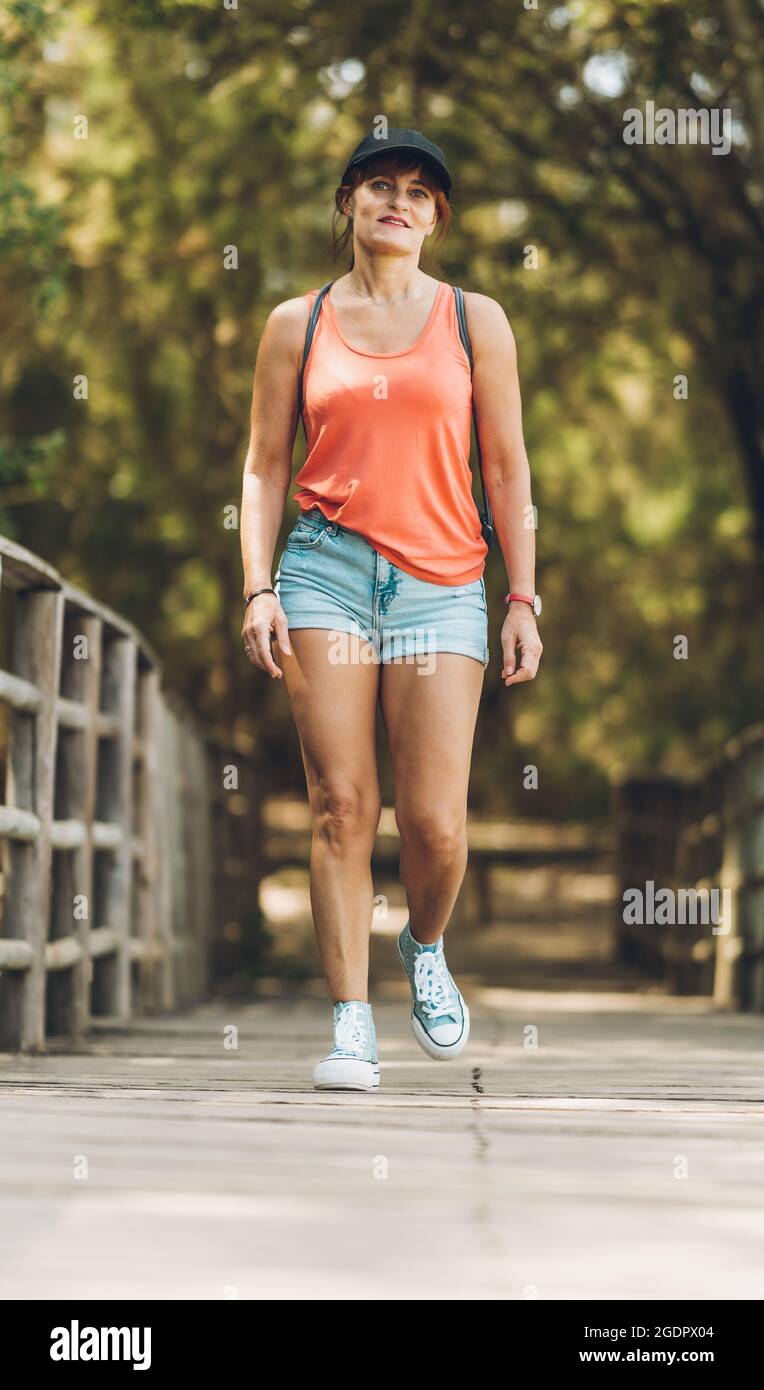 Donna che cammina lungo un sentiero in legno in abiti estivi Foto Stock