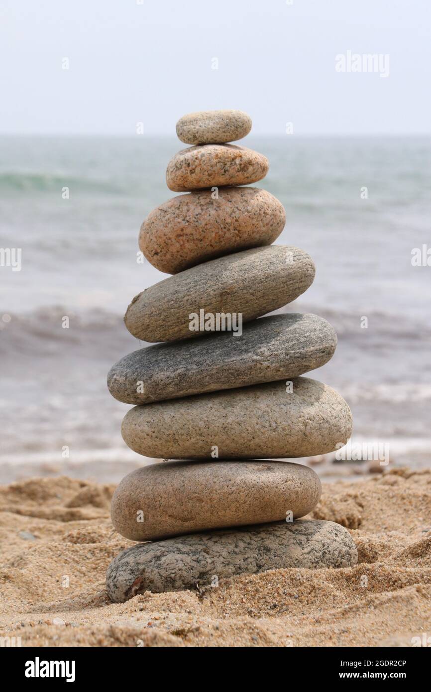 Una torre bilanciata di rocce spiaggia lisce sulla sabbia vicino all'oceano Foto Stock
