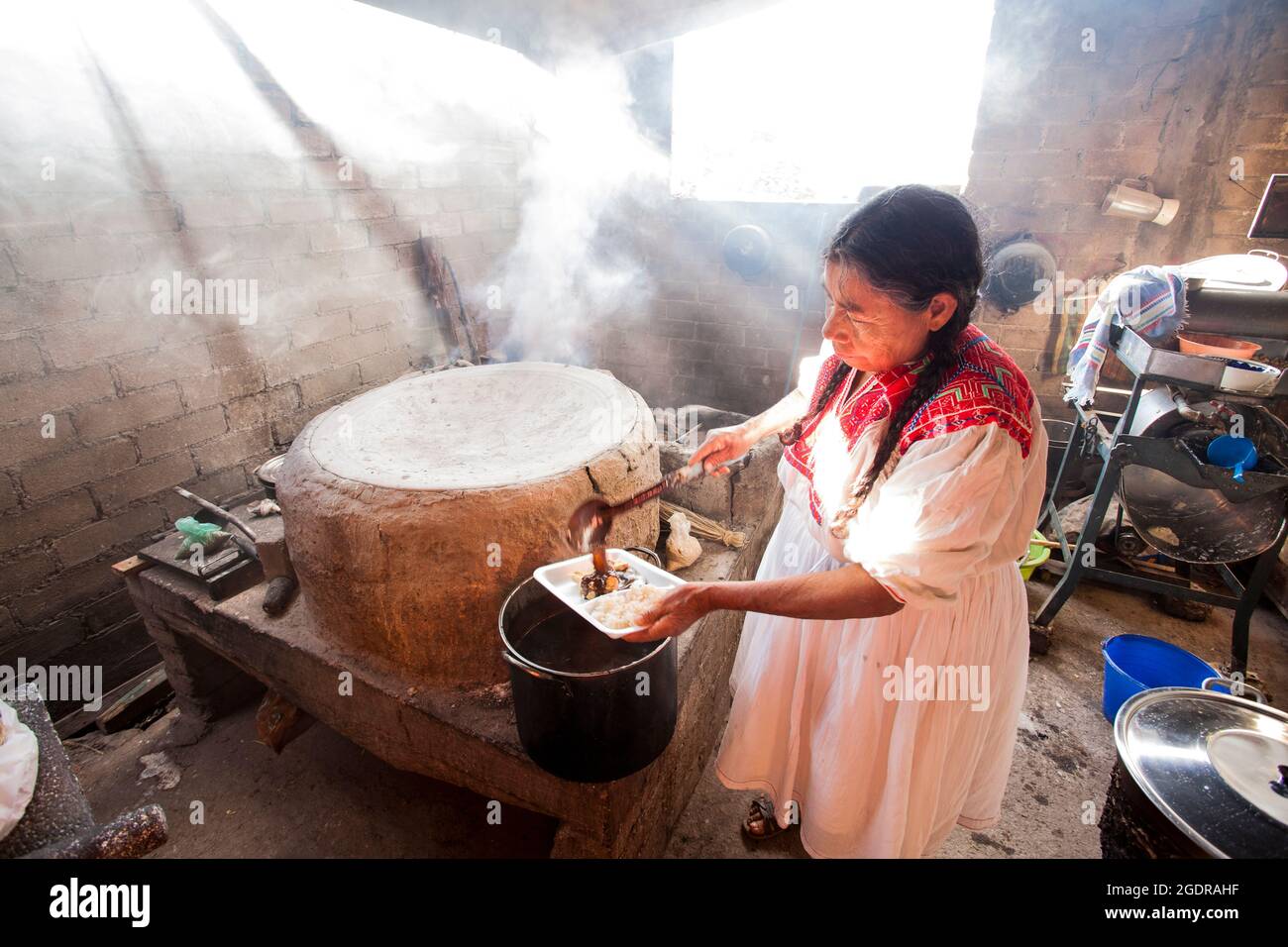 Una donna indigena anziana serve una talpa tradizionale nel villaggio di San Vicente Coatlan, Oaxaca, Messico. Foto Stock