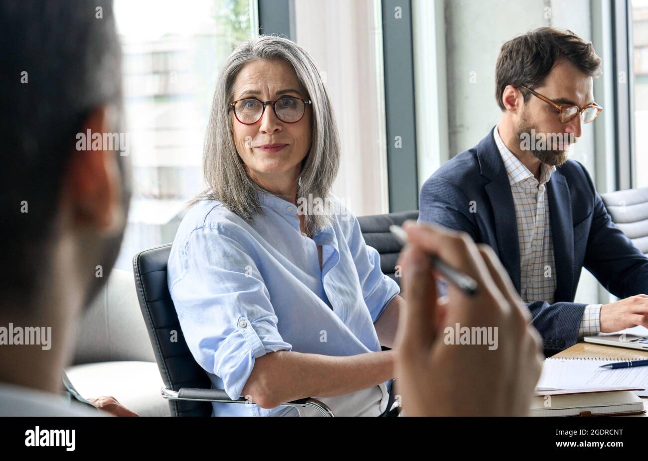 Sorridente ceo femminile che guarda il collega del manager maschile alla riunione del tavolo. Foto Stock