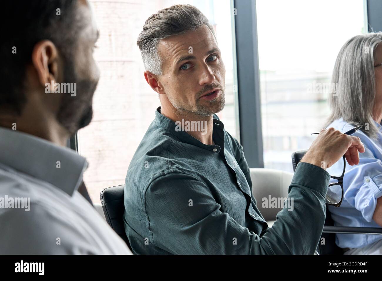 Amministratore delegato serio e maturo che parla con il manager afro-americano in sala riunioni. Foto Stock
