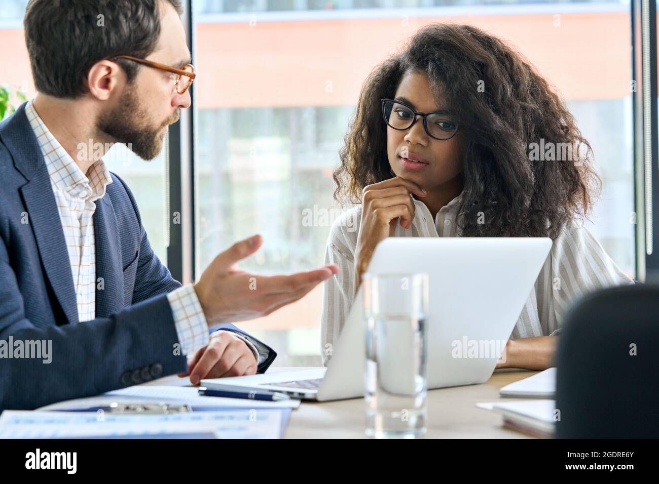 Capo mentore maschile che parla con una tirocinante femminile durante la riunione nella sala riunioni. Foto Stock