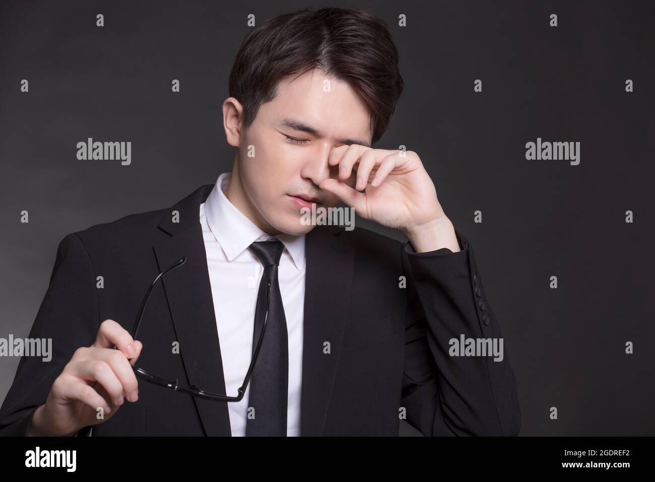 Uomo d'affari che si sente malato e stanco, giovane uomo che sfrega gli occhi Foto Stock