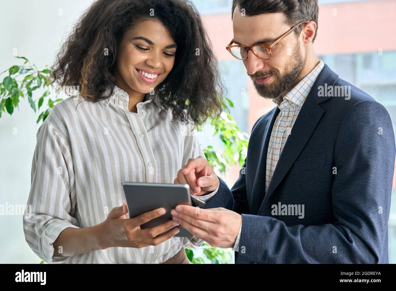 il ceo di Mentor che tiene un dispositivo tablet e il manager femminile discutono del progetto in ufficio. Foto Stock
