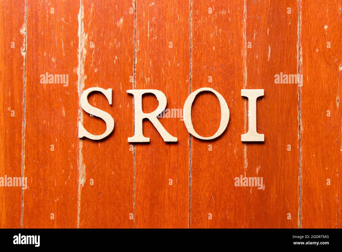 Lettera alfabetica in parola SROI (abbreviazione di Social Return on Investment) sul vecchio colore rosso sfondo della piastra in legno Foto Stock