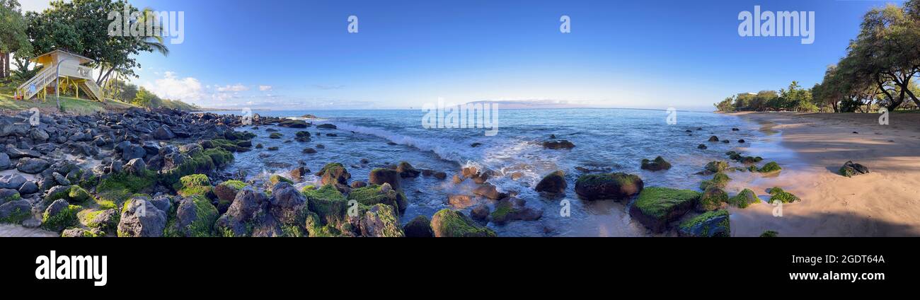 Le onde oceaniche lambiscono le coste dorate e le rocce disseminate di alghe di Ka'anapali Beach a Lahaina, Hawaii. Foto Stock