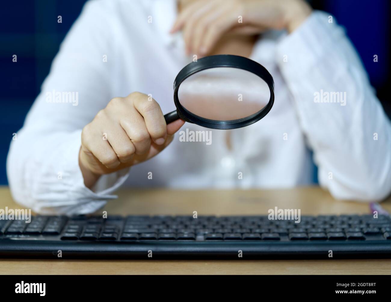 Un uomo d'affari controlla l'apparecchiatura del calcolatore con una lente d'ingrandimento concetti di sicurezza delle informazioni del Internet. Foto Stock