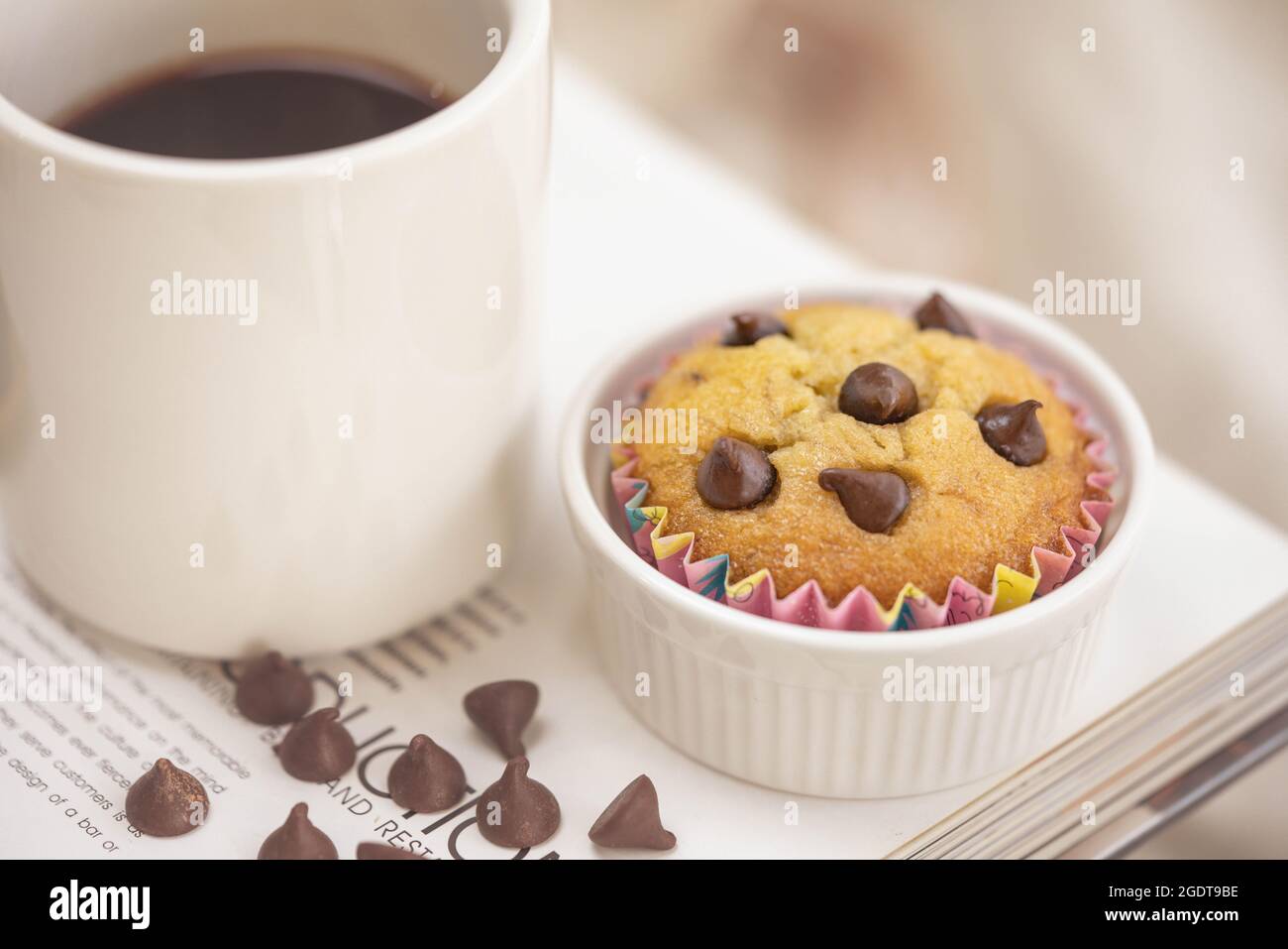 Caffè nero e muffin freschi fatti in casa a base di banana decorati con gocce di cioccolato sul tavolo Foto Stock