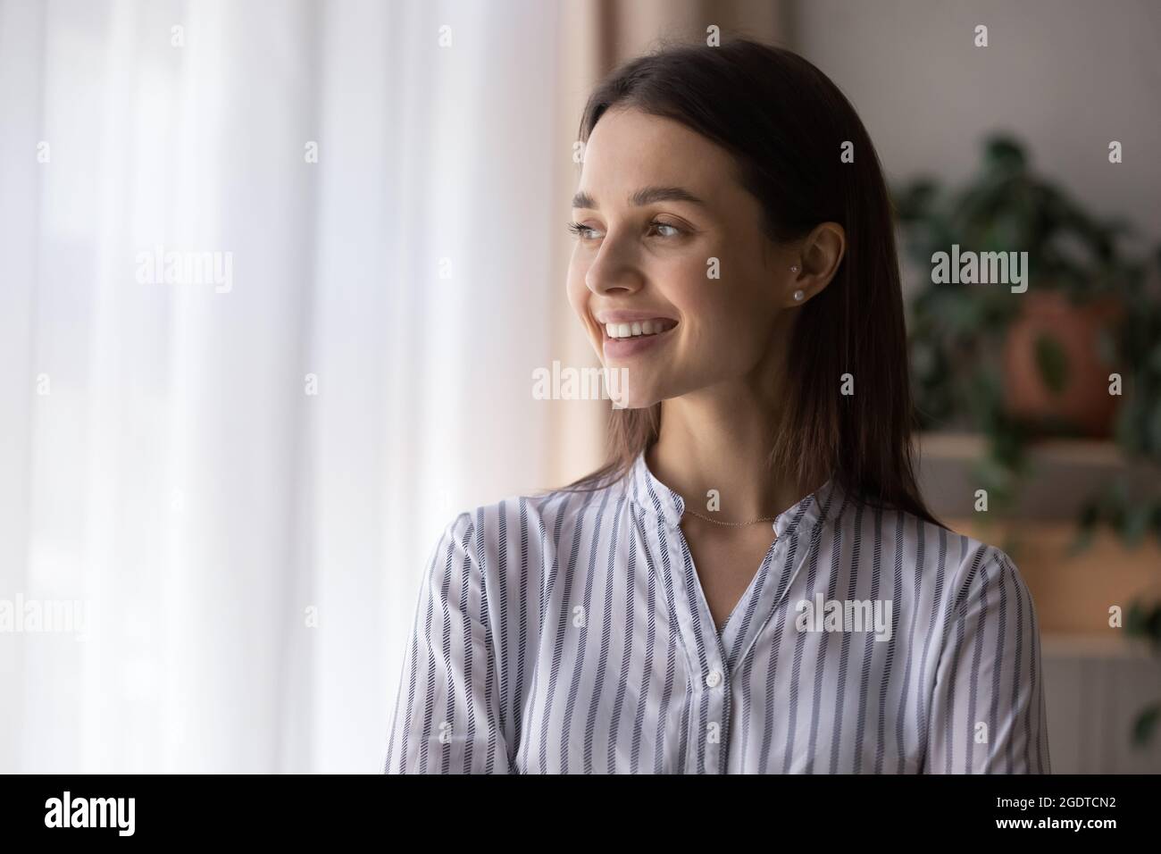 Donna sorridente guarda a distanza pensando al successo Foto Stock