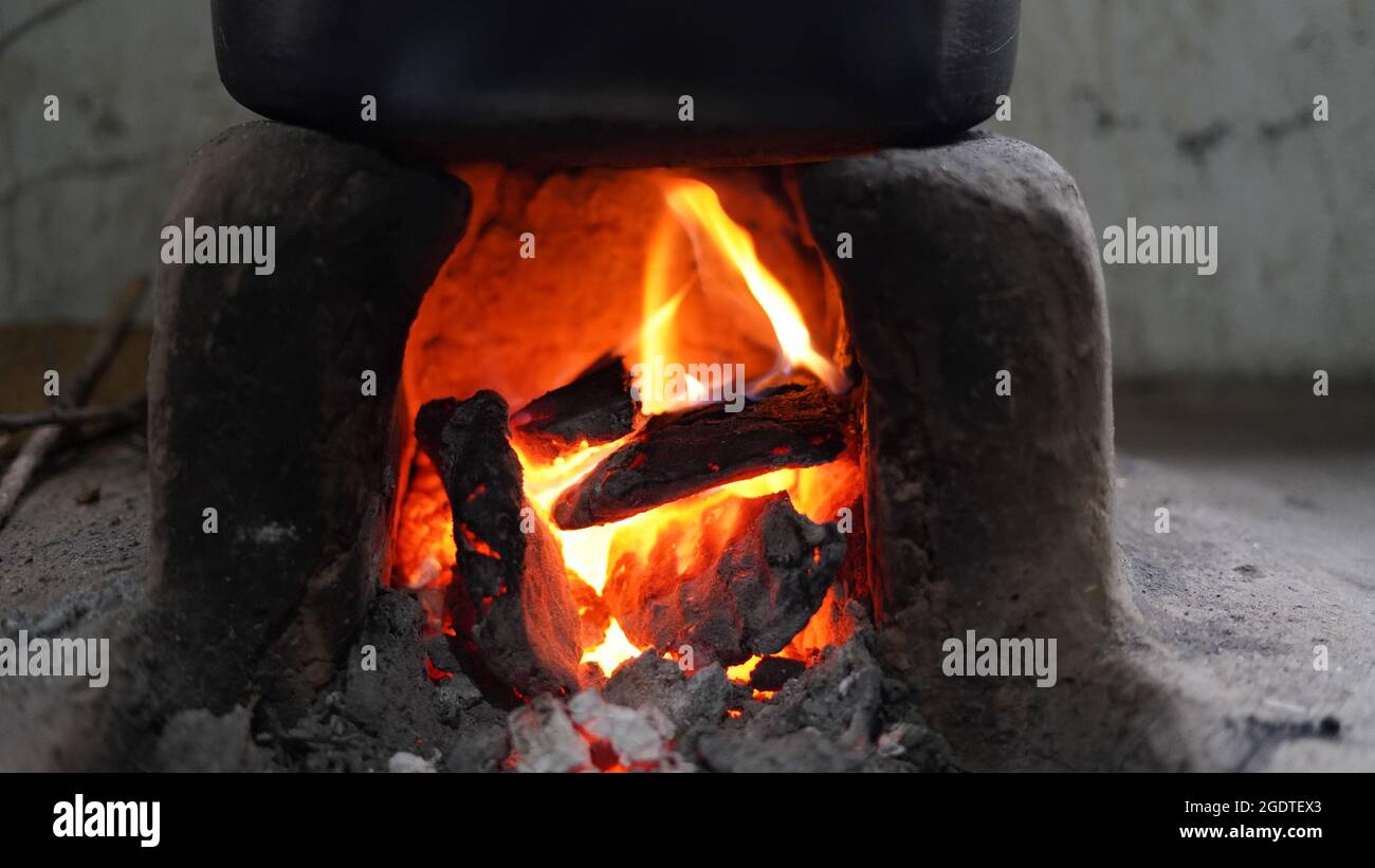 Forno di argilla naturale tradizionale indiano. Abitanti del villaggio che cucinano al mattino usando la legna da ardere come carburante per il campeggio. Foto Stock