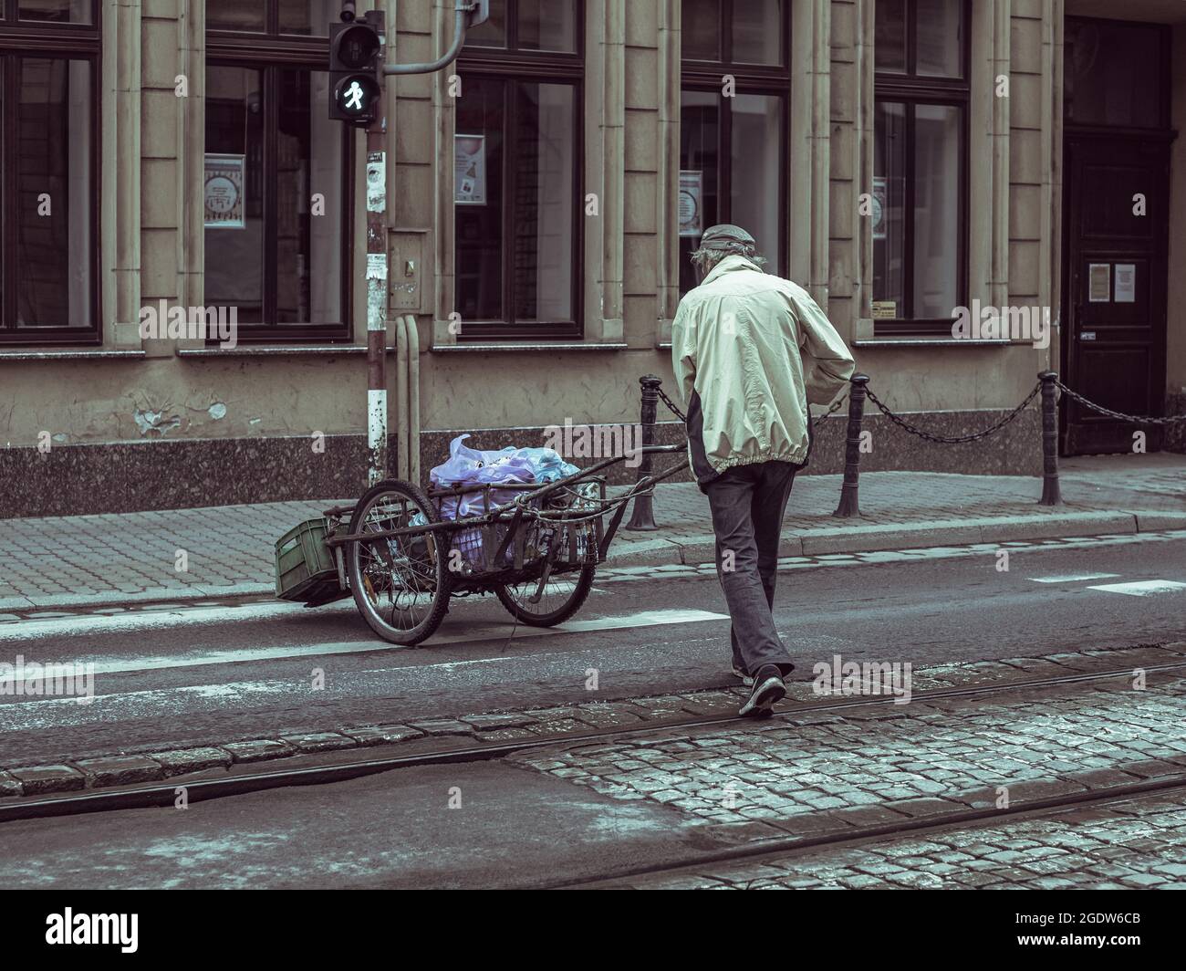 uomo che spinge un carrello con carichi, fotografia di strada Foto Stock