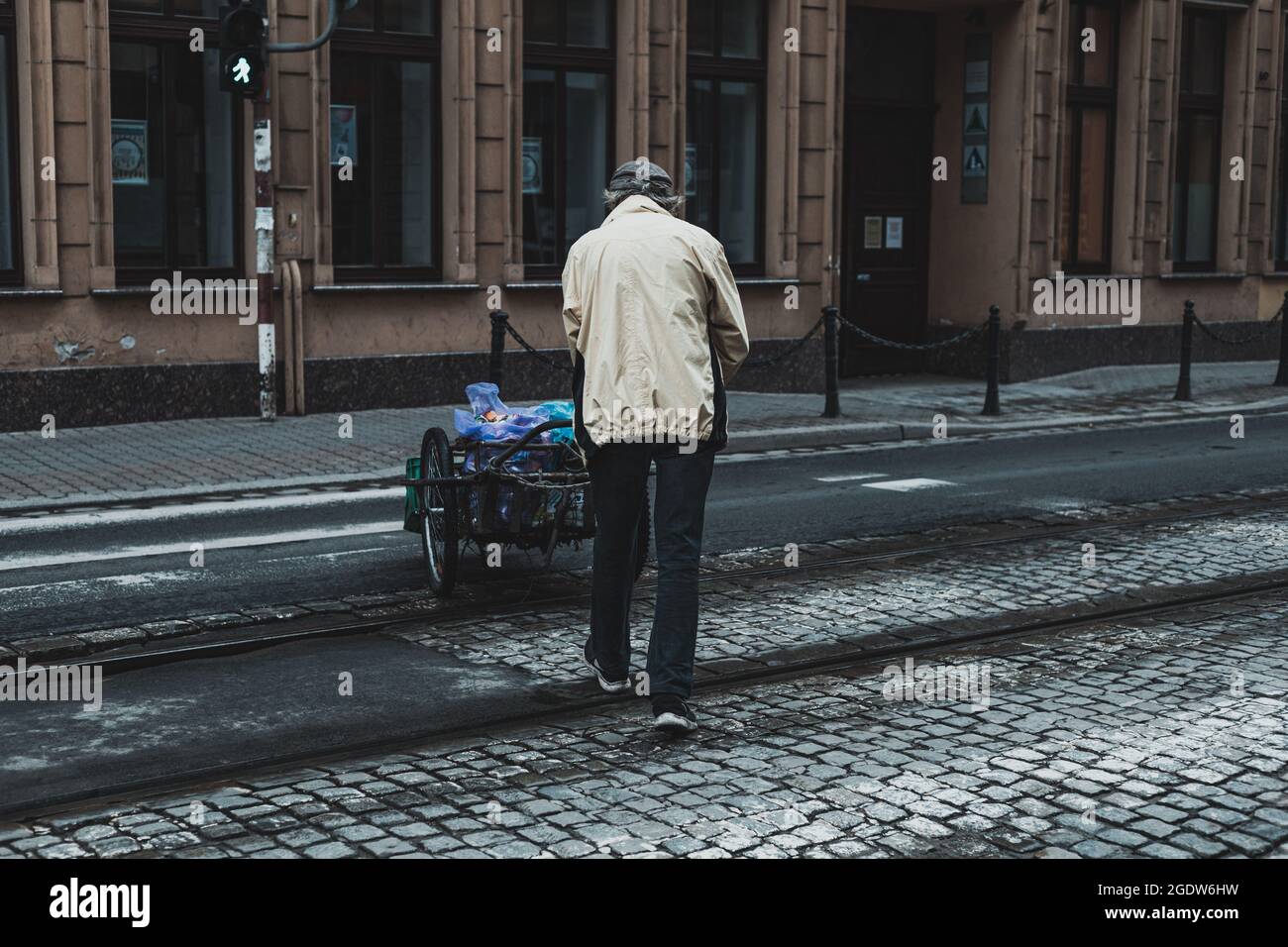 uomo che spinge un carrello con carichi, fotografia di strada Foto Stock
