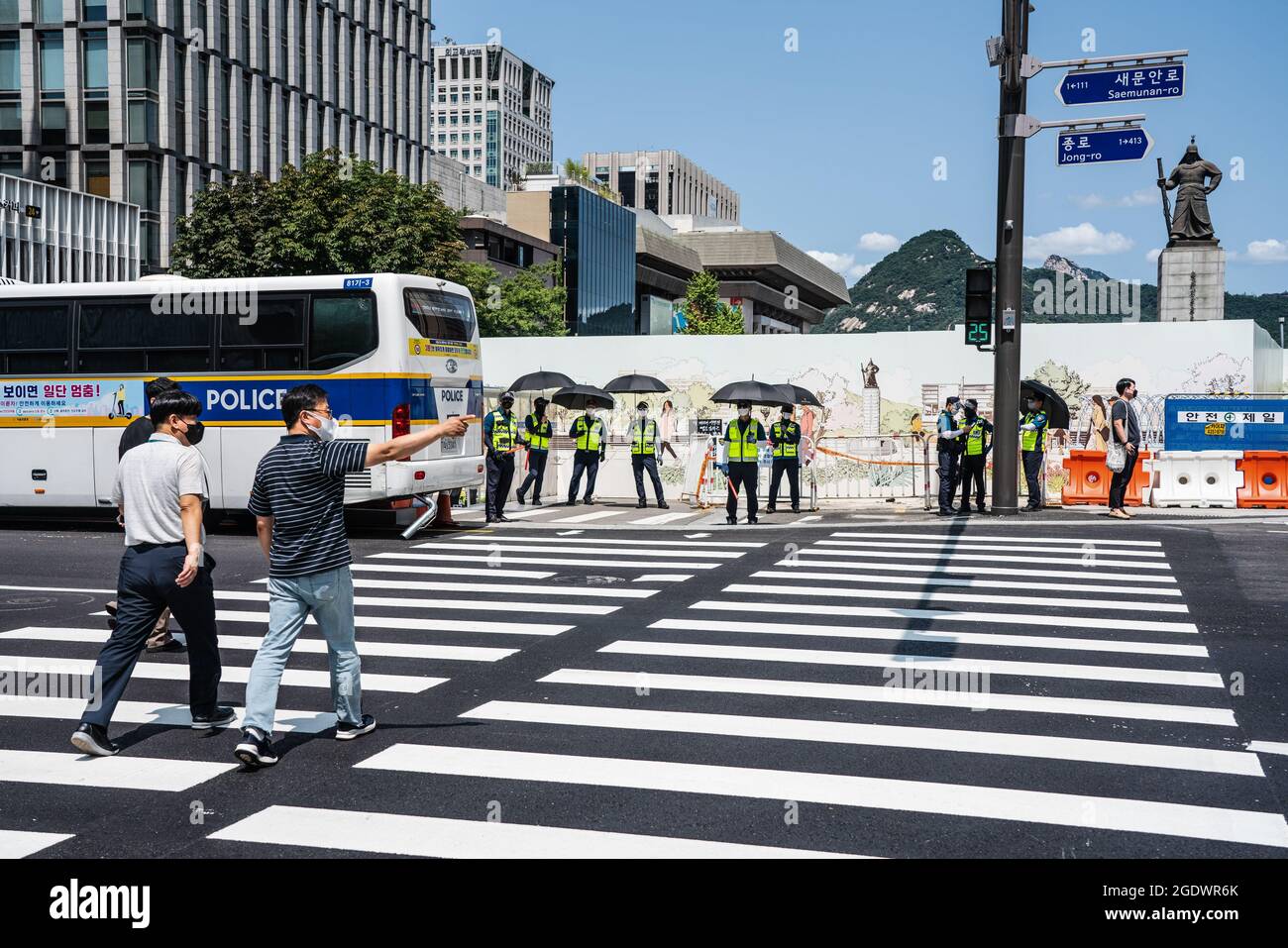 Seoul, Corea del Sud. 15 agosto 2021. Le persone che indossano maschere per il viso attraversano la strada a Seoul. La polizia sudcoreana allestisce le mura degli autobus e i punti di controllo per bloccare i manifestanti a Seul. La Corea del Sud ha vietato le proteste prima della Giornata Nazionale di Liberazione, in previsione della ripresa dell’epidemia di coronavirus causata da un raduno anti-governo lo scorso agosto. Credit: SOPA Images Limited/Alamy Live News Foto Stock