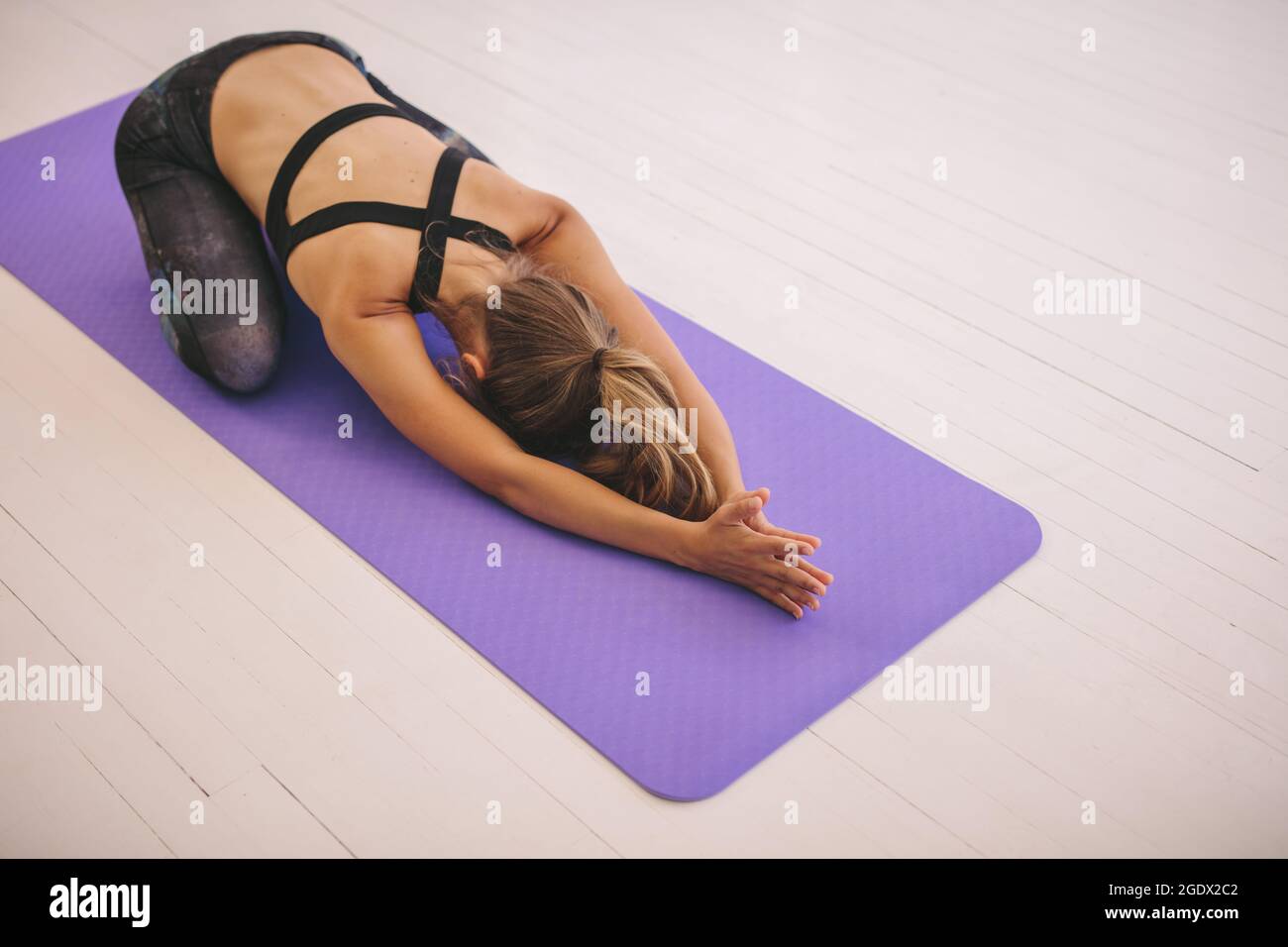 Donna che fa esercizio di stretching sul tappetino da yoga. fitness femminile che esegue yoga su un tappetino in palestra. Posa di un bambino, Balasana. Foto Stock