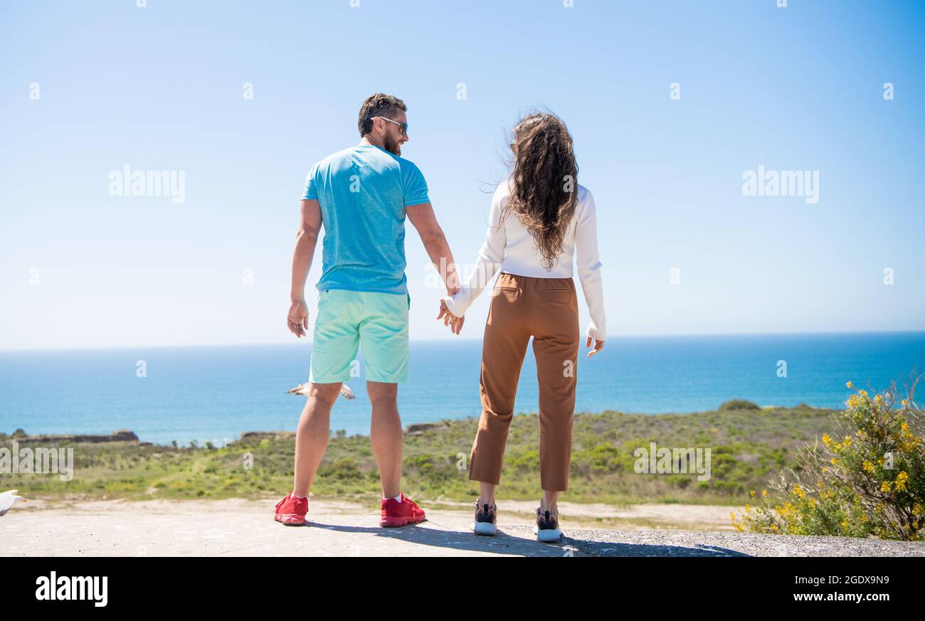 giovane coppia di famiglia che tiene le mani guardando l'acqua di mare dall'alto, libertà Foto Stock