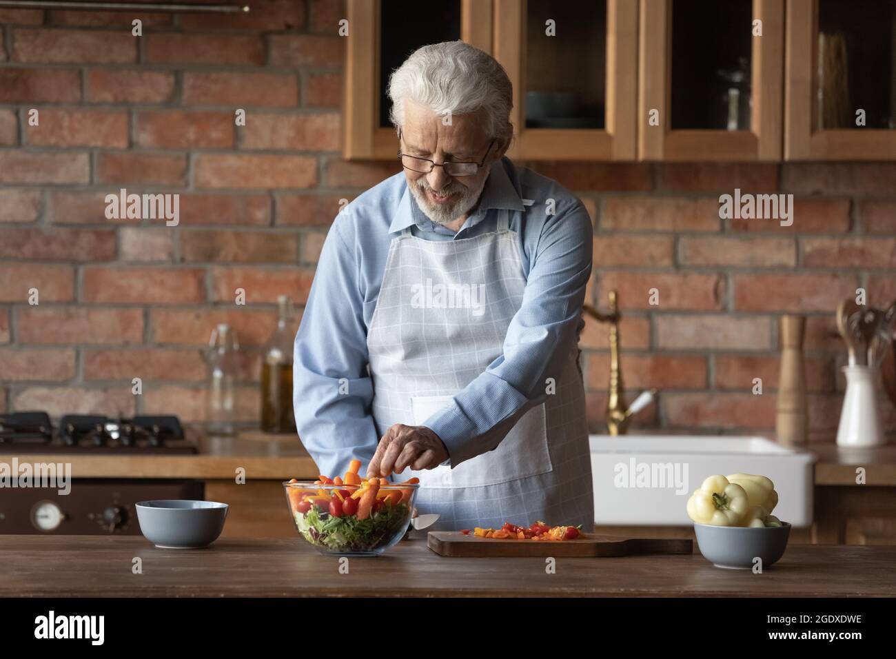 Felice vecchio uomo caucasico cucina cibo a casa Foto Stock