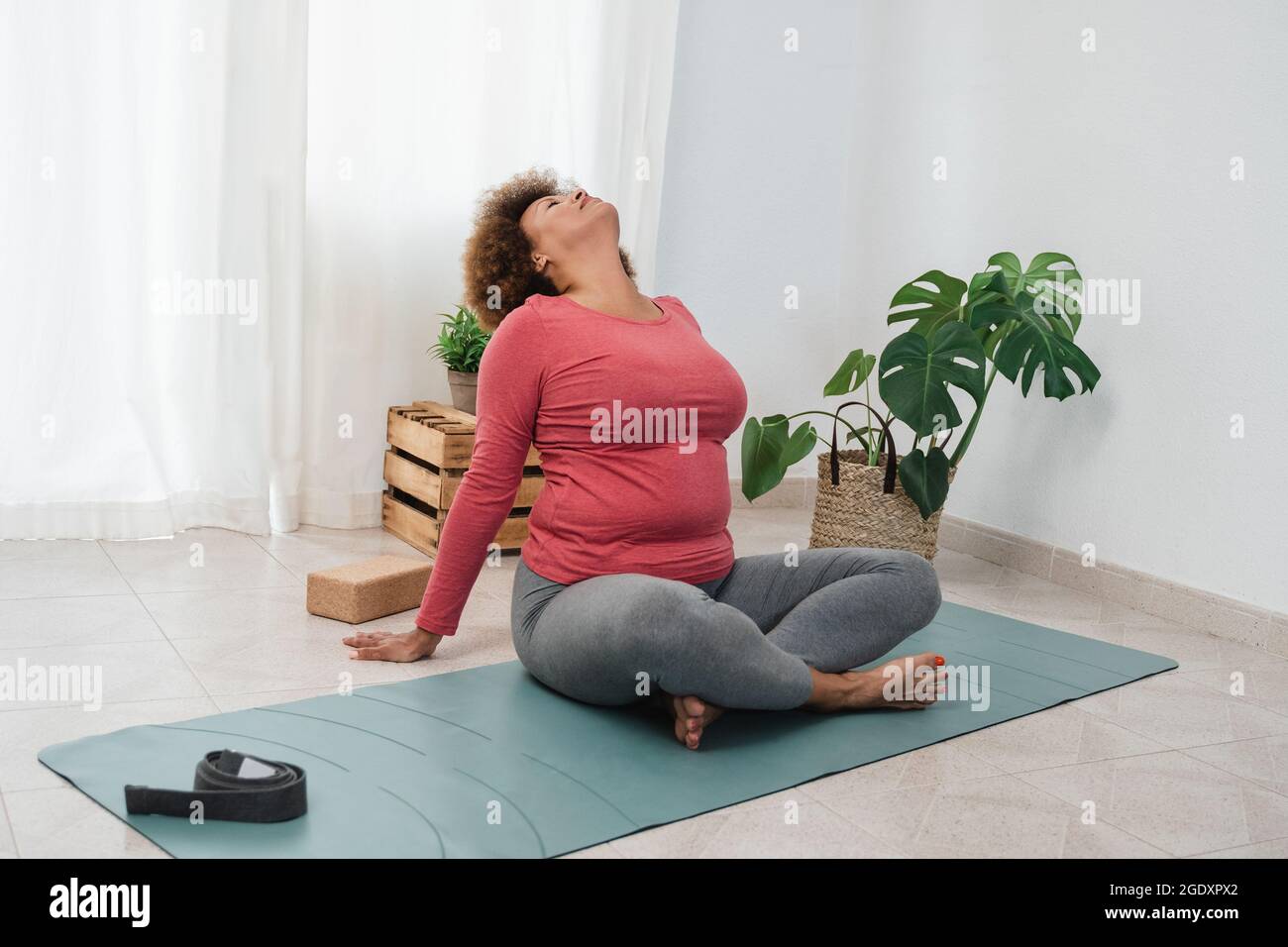 Donna anziana africana che fa esercizi di yoga a casa - formazione e stile di vita sano - Focus sul viso Foto Stock