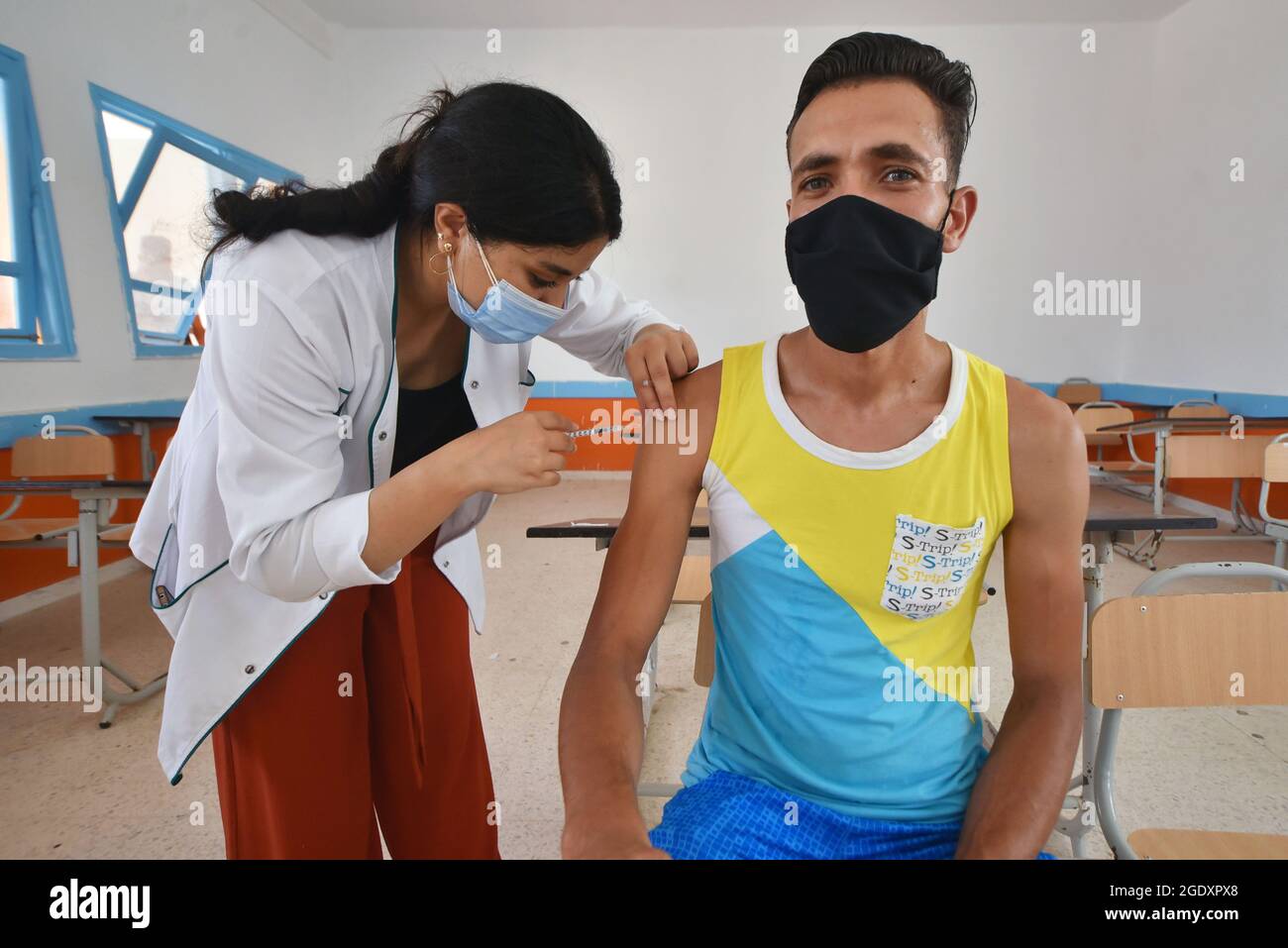 Un operatore sanitario somministra una dose di vaccino moderna COVID-19 ad un uomo in un centro di inoculazione in un edificio della scuola superiore nella capitale Tunisi. Il Direttore sanitario tunisino, Generale Faycel ben Salah, ha detto che circa 1 milione di persone saranno chiamate al secondo giorno di vaccinazione intensiva del coronavirus, per i gruppi di 18-39 anni. (Foto di Jdidi Wassim / SOPA Images/Sipa USA) Foto Stock