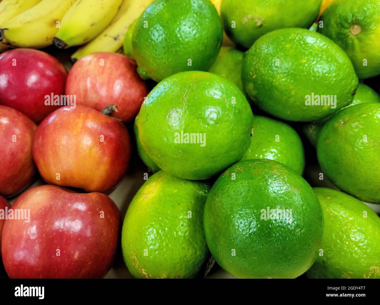 Primo piano di lime e mele rosse con banane mature sul mercato agricolo Foto Stock