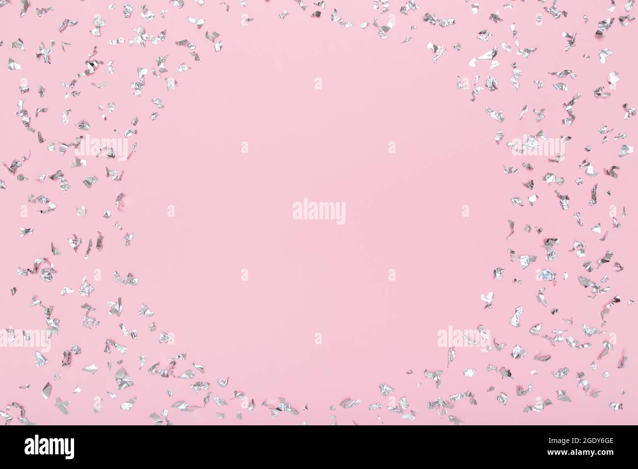 Cornice rotonda di confetti con glitter argento scintillante su sfondo rosa pastello. Disposizione piatta, vista dall'alto. Festa, festa, sfondo festa. Simulato in su per il vostro progetto. Foto Stock