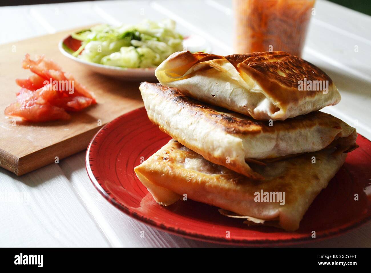 Pane piatto arrosto (lavasch) con ripieno di verdure sul piatto rotondo rosso, fuoco selettivo Foto Stock