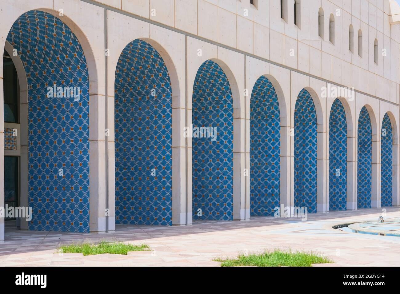 Vista prospettica sulla facciata della parete dell'edificio con fila di archi orientali ornate da piastrelle di stile arabesco blu Foto Stock