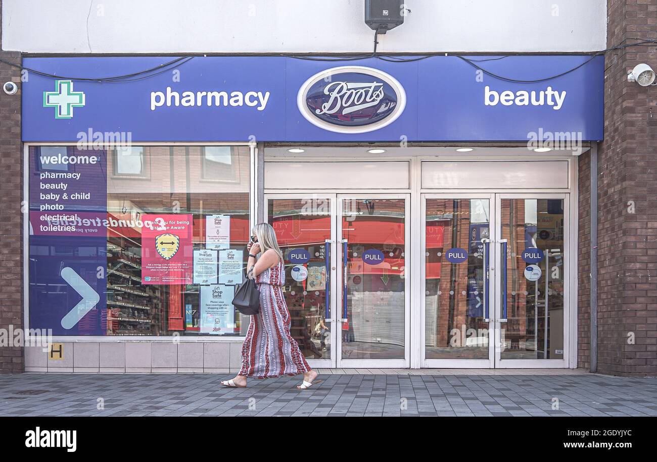 Lisburn, Regno Unito. 18 luglio 2021. Una donna al telefono cammina oltre Boots Farmacia e negozio di bellezza su Bow Street a Lisburn. Credit: SOPA Images Limited/Alamy Live News Foto Stock